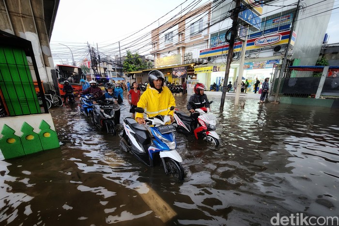 Pemotor menuntun kendaraannya untuk menerobos banjir di Jalan Ciledug Raya, Kelurahan Petukangan, Kecamatan Pesanggrahan, Jakarta Selatan, Kamis (1/12/2022). Banjir akibat hujan deras. Foto diambil pukul 18.00 WIB.