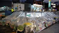 Seorang petugas polisi berjaga di dekat tumpukan karangan buka di Itaewon, Seoul, Korea Selatan, Selasa (29/11/2022).  