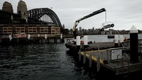 Sebuah mobil berwarna silver digantung di atas pelabuhan Sydney, Campbell Cove , Australia, Rabu (30/11/2022).