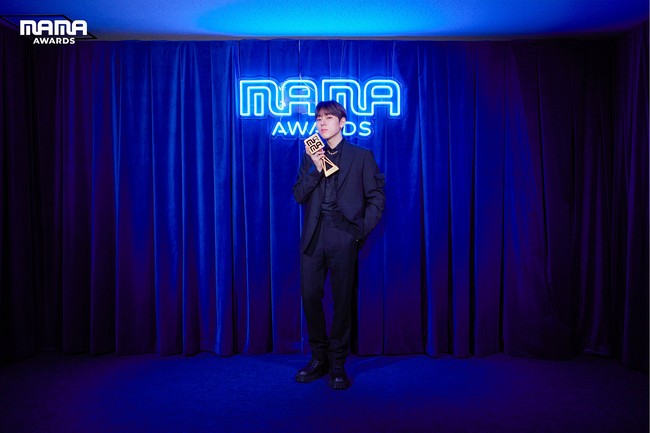 ZICO sukses mempopulerkan tren dance challenge TikTok di kalangan idol KPop pada 2020 berkat lagu Any Song. Dia menerima penghargaan Global Music Trend Leader dalam balutan jas serba hitam dengan aksen kalung rantai yang serasi dengan pialanya. Foto: dok. Twitter @MnetMAMA