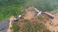 Material longsoran menutup akses jalan dan menimpa sejumlah kendaraan.