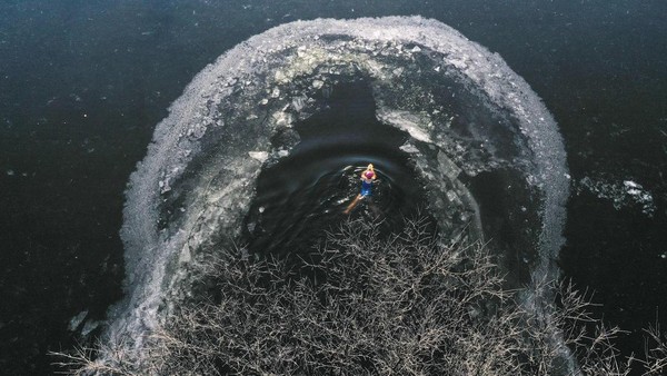 Seorang warga berenang di danau yang sebagian membeku di Shenyang, Liaoning, China, Rabu (30/11/2022).  