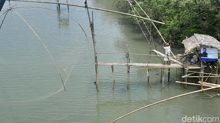 Seorang nelayan tengah menangkap ikan dengan bagang