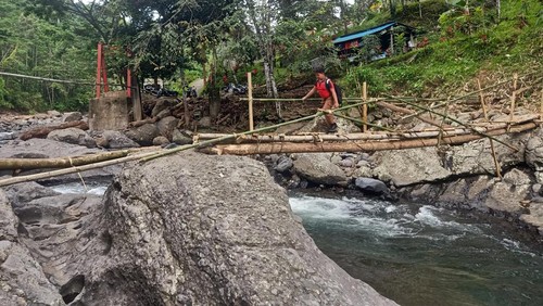 Seorang siswa melintasi jembatan darurat di Sungai Gelar, Banjar Palungan Batu, Desa Batuagung, Kecamatan Jembrana, Kabupaten Jembrana, Jumat (02/12/2022).