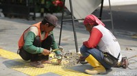Dua pekerja membongkar trotoar sebagai langkah awal proses revitalisasi.  