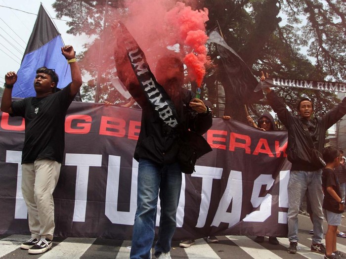 Suporter Arema FC (Aremania) menyalakan api suar (flare) saat berunjuk rasa dan memblokir jalan di perempatan jalan Ciliwung, Malang, Jawa Timur, Minggu (4/12/2022). Unjuk rasa dengan memblokir jalan selama dua jam yang dilakukan Aremania di sejumlah titik di Kota Malang tersebut merupakan bentuk protes terhadap aparat penegak hukum atas penanganan kasus Tragedi Kanjuruhan yang dinilai jalan di tempat. ANTARA FOTO/Ari Bowo Sucipto/aww.