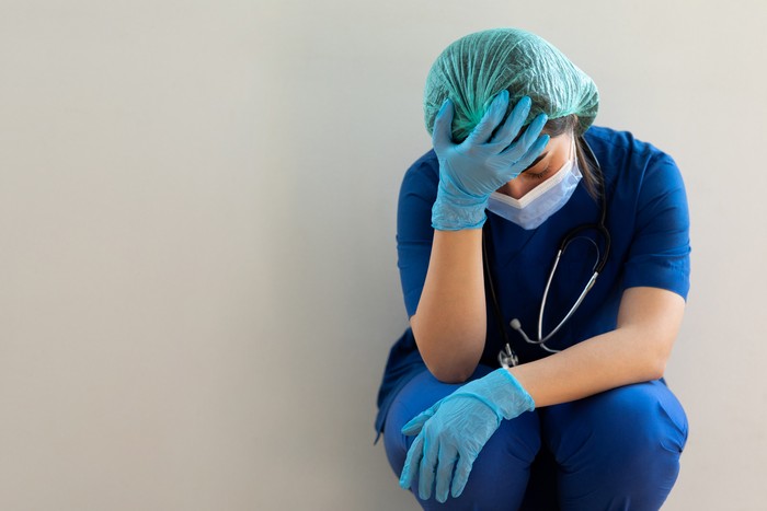 Nurse in a corridor while holding her head in a hospital