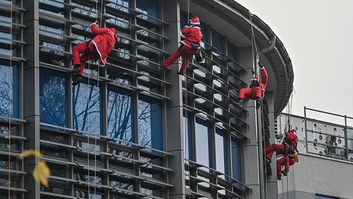 KRAKOW, POLAND - DECEMBER 04: Climbers dressed in Santa Claus clothing entertain sick children through the windows at the Pediatric hospital in Krakow, Poland on December 04, 2022. For the 17th time, Moto Santa Claus initiative visits Pediatric hospitals in Krakow to bring presents and joy to little patients undergoing treatments. Apart from the visit, the initiative also organize money collection to help to buy presents for all the 407 children under treatment in the city of Krakow. (Photo by Omar Marques/Anadolu Agency via Getty Images)