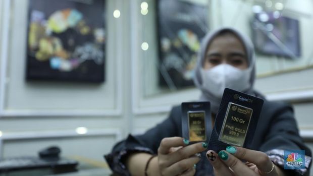 Karyawan menunjukkan emas Antam di gerai Galeri 24 Pegadaian di Jakarta, Senin (5/12/2022). Harga emas batangan di PT Pegadaian bergerak stagnan pada perdagangan hari ini, Senin (5/12/2022). Pegadaian sendiri menjual berbagai jenis emas, yaitu emas Antam, Antam Retro, Antam Batik, dan UBS. Ukurannya pun dijual beragam, mulai dari 0,5 gram hingga 1.000 gram. Pada perdagangan hari ini, harga emas Antam ukuran 1 gram dibanderol Rp 1.033.000. (CNBC Indonesia/Tri Susilo)
