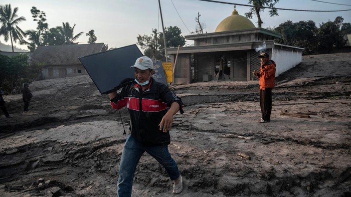 Korban Erupsi Semeru Selamatkan Barang-barang Berharga People salvage their belongings following a volcanic eruption by Mount Semeru at Kajar Kuning village in Lumajang on December 5, 2022. - Indonesia's Mount Semeru erupted on December 4 spewing hot ash clouds a mile high and rivers of lava down its side while sparking the evacuation of nearly 2,000 people exactly one year after its last major eruption killed dozens. (Photo by JUNI KRISWANTO / AFP) (Photo by JUNI KRISWANTO/AFP via Getty Images)