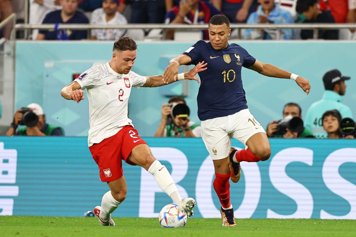 DOHA, QATAR - DECEMBER 04: Kylian Mbappe of France embraces Matty Cash of Poland following the final whistle of during the FIFA World Cup Qatar 2022 Round of 16 match between France and Poland at Al Thumama Stadium on December 04, 2022 in Doha, Qatar. (Photo by Youssef Loulidi/Fantasista/Getty Images)