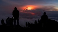 Orang-orang berkumpul untuk menyaksikan letusan Gunung Mauna Loa saat aliran lava tertutup awan di Hawaii, AS, Sabtu (3/12/2022).  