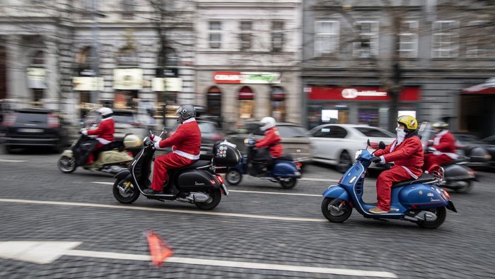 Vespa enthusiasts dressed in Santa Claus costumes take part in a charity ride in support of 'Kapka Nadeje', a foundation that helps sick children, at Wenceslas Square in Prague on December 4, 2022. (Photo by Michal Cizek / AFP) (Photo by MICHAL CIZEK/AFP via Getty Images)