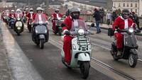 Para pengendara yang berkostum Sinterklas konvoi dengan Vespa di kota Praha, Ceko, Minggu (4/12/2022).  