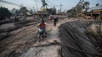 Warga melintas di jalan yang penuh material lahar dingin. Juni Kriswanto/AFP/Getty Images.
