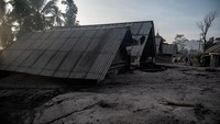 Abu vulkanik tampak menimbun rumah-rumah warga desa di kaki Gunung Semeru. (Juni Kriswanto/AFP/Getty Images)