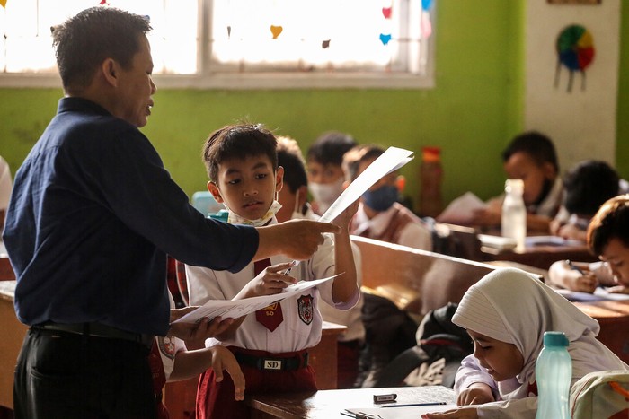 Guru pengawas memberikan kertas ujian Penilaian Akhir Semester (PAS) di SDN Pondok Cina 1, Depok, Jawa Barat, Selasa (6/12/2022). Pekan ujian Penilaian Akhir Semester (PAS) yang berlangsung sampai 9 Desember tersebut menjadi pekan terakhir para siswa berkegiatan belajar mengajar sebelum direlokasi ke SDN Pocin 3 dan SDN Pocin 5 dikarenakan lahan sekolah itu akan dijadikan masjid. ANTARA FOTO/Asprilla Dwi Adha/rwa.