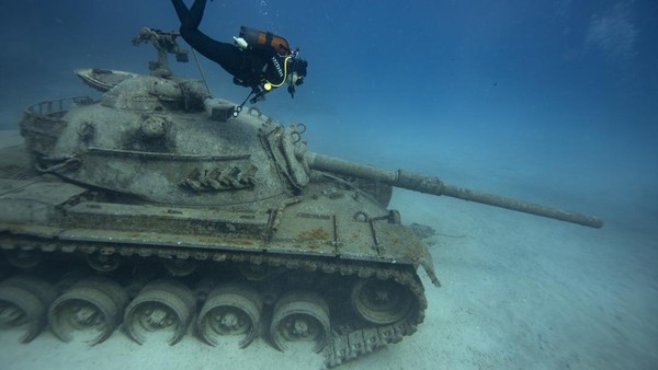 Seorang penyelam terlihat di dekat sebuah tank di perairan Pulau Guvercin, distrik Kas Antalya, Turki, Minggu (4/12/2022).  