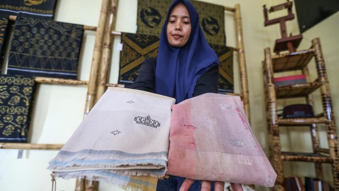 Pengunjung mencoba pakaian dari kain tenun Tidore di Rumah Tenun Puta Dino Kayangan, Kota Tidore Kepulauan, Maluku Utara.