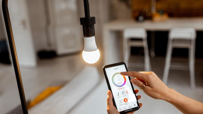 Controlling light bulb temperature and intensity with a smartphone application. Concept of a smart home and managing light with mobile devices