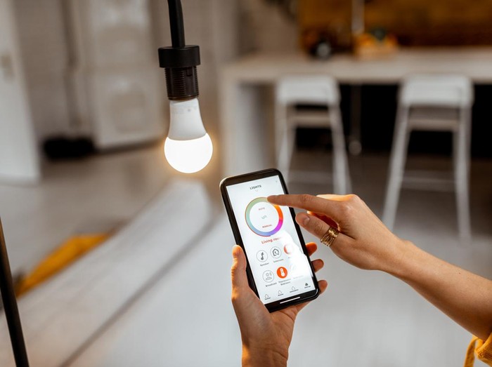 Controlling light bulb temperature and intensity with a smartphone application. Concept of a smart home and managing light with mobile devices