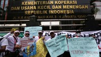 Massa membentangkan berbagai poster penolakan di depan Gedung Kementerian Koperasi dan Usaha Kecil Menengah (UKM).