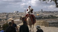 Issa Kassissieh menaiki unta di Bukit Zaitun yang menghadap ke Kota Tua Yerusalem.