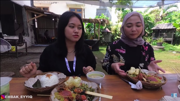 Wanita berhijab makan sate babi