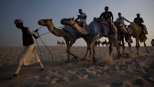 Selain mengendarai mobil, untuk melengkapi pengalaman berkeliling padang pasir, kamu juga bisa menunggang unta pada sore hari. (Natalia Kolesnikova/AFP/Getty Images)  