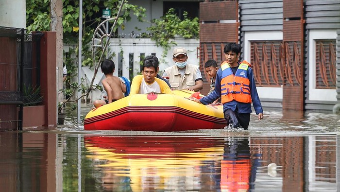 BANJIR AKIBAT KALI TERTUTUP LONGSOR Sejumlah warga berjalan melintasi banjir di Perumahan Pondok Tirta Mandala, Depok, Jawa Barat, Kamis (8/12/2022). Tingginya curah hujan tinggi pada Rabu (7/12/2022) serta adanya longsor yang menutupi aliran Kali Jantung menyebabkan kali yang berada di wilayah tersebut meluap dan menggenanangi permukiman warga.