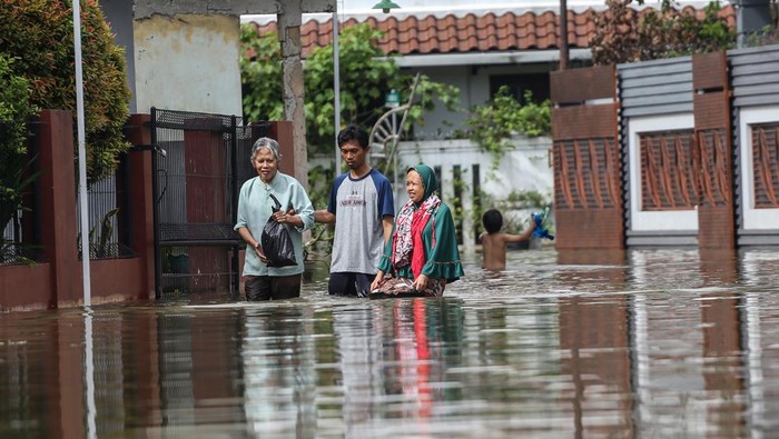 BANJIR AKIBAT KALI TERTUTUP LONGSOR Sejumlah warga berjalan melintasi banjir di Perumahan Pondok Tirta Mandala, Depok, Jawa Barat, Kamis (8/12/2022). Tingginya curah hujan tinggi pada Rabu (7/12/2022) serta adanya longsor yang menutupi aliran Kali Jantung menyebabkan kali yang berada di wilayah tersebut meluap dan menggenanangi permukiman warga.