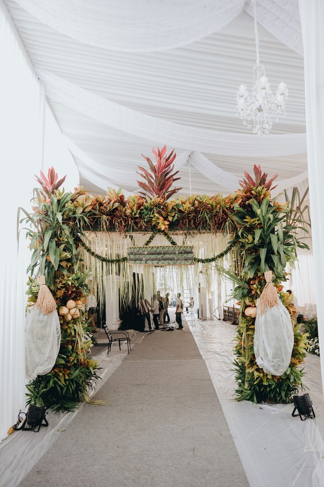 Tamu disambut dengan gerbang floral yang berhiaskan tanaman hias seperti Aglaonema atau Sri Rejeki. Sesuai namanya, tanaman tersebut diyakini dapat membawa keberuntungan. (Foto: Morden/Bride Story)