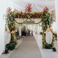 Tamu disambut dengan gerbang floral yang berhiaskan tanaman hias seperti Aglaonema atau Sri Rejeki. Sesuai namanya, tanaman tersebut diyakini dapat membawa keberuntungan. (Foto: Morden/Bride Story)