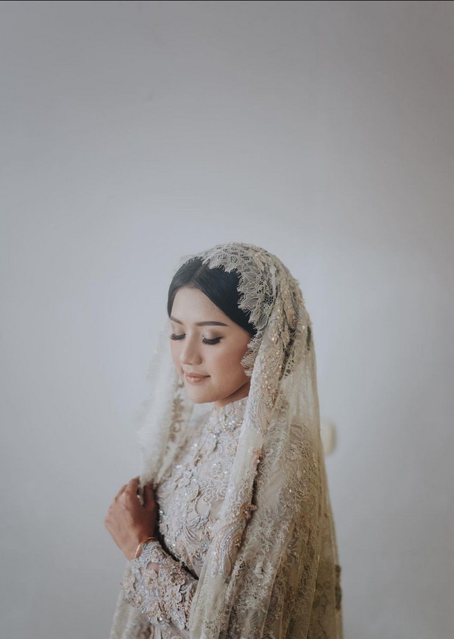 Anak ketiga dari empat bersaudara ini memilih gaun lace warna abu-abu dengan detail bordir dan payet dari koleksi Lace by ARTKEA. Gaun hadir dalam set lengkap dengan kerudung dan sepatu. Foto: Instagram/@thebridestory