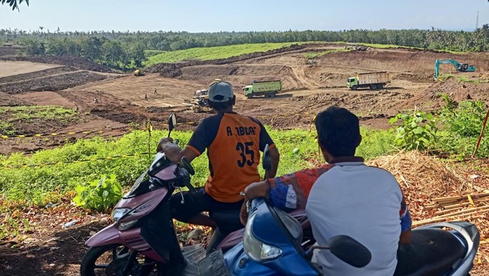 Warga melihat pengerjaan Tol Gilimanuk-Mengwi yang masih dalam tahapan perataan lahan di Banjar Sumbermis, Desa Pekutatan, Kecamatan Pekutatan, Kabupaten Jembrana, Bali, Kamis (8/12/2022).