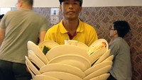 Pelayan ini punya keahlian yang tinggi dalam membersihkan belasan piring kotor dari atas meja pengunjung. Foto: Pool/site