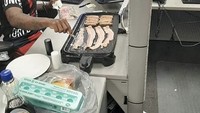 Pekerja ini juga tampak heboh ketika makan siang. Bekal makanannya ia buat sendiri di kantor menggunakan mesin pemanggang. Ia tampak membuat bacon dan sosis panggang. Foto: site news