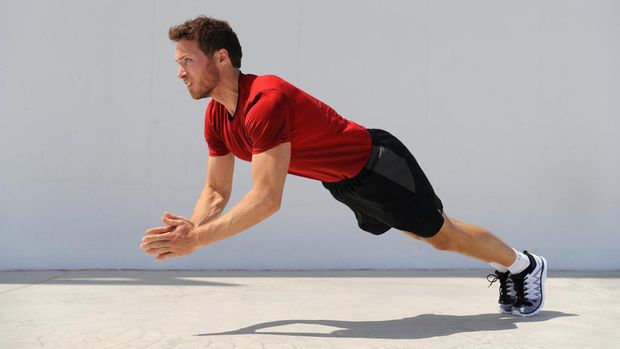 Clap pushup fitness man doing plyometrics push-up explosive workout for muscles training. Athlete working out on gym floor.