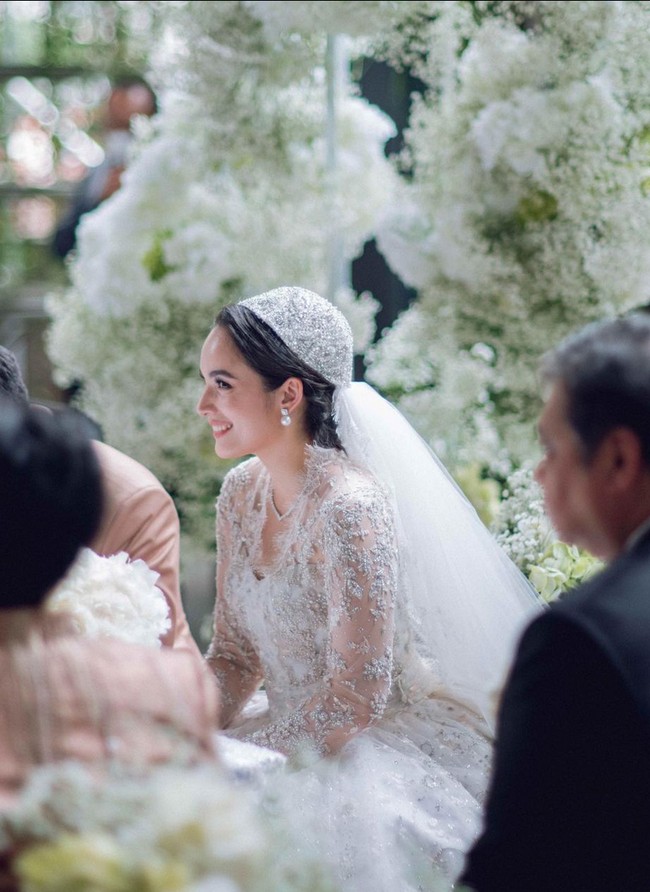Gaun lengan panjang dengan leher berpotongan V ini tampak mewah berhias payet, mutiara serta kristal. Sekilas, gaun ini mengingatkan pada busana pengantin Grace Kelly dan Kate Middleton. Foto: Instagram/@lxemonents @iluminen