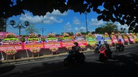 Pengendara motor melintas di depan deretan karangan bunga ucapan selamat kepada Kaesang Pangarep dan Erina Gudono di kawasan Pura Mangkunegaran, Solo, Jawa Tengah, Sabtu (10/12/2022).