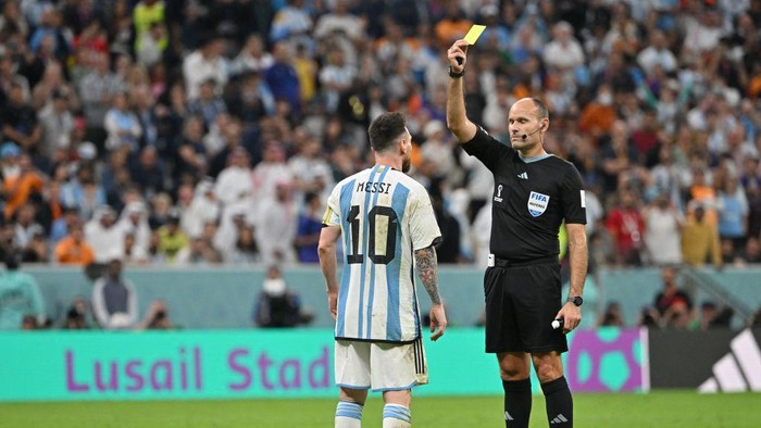 Spanish referee Antonio Mateu Lahoz shows a yellow card to Argentinas forward #10 Lionel Messi during the Qatar 2022 World Cup quarter-final football match between Netherlands and Argentina at Lusail Stadium, north of Doha, on December 9, 2022. (Photo by Alberto PIZZOLI / AFP) (Photo by ALBERTO PIZZOLI/AFP via Getty Images)
