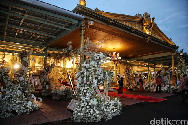 Rangkaian bunga segar langsung menyambut tamu di depan teras Pendopo.  Semua serba putih, mulai dari mawar, anggrek bulan, bunga lily, hingga baby’s breath, sehingga memberikan sentuhan elegan. Apalagi ketika berpadu apik dengan detail emas yang menghiasi arsitektur Jawa klasik dari bangunan tersebut. (Foto: Pradita Utama/detikcom)