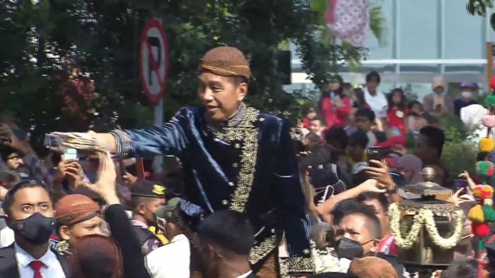 Momen Jokowi membagikan suvenir saat kirab, Minggu (11/12/2022).