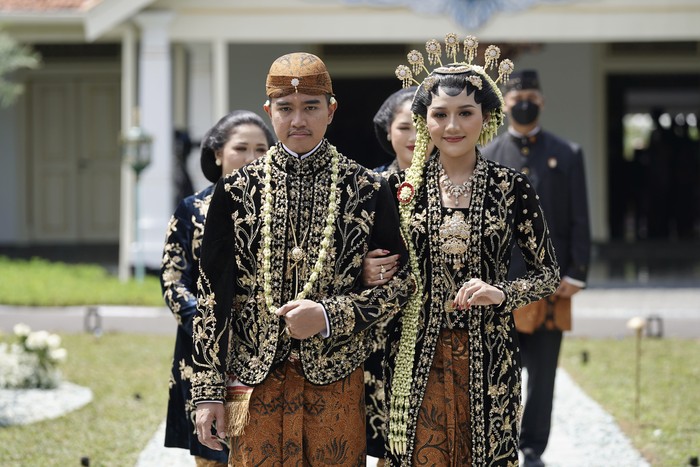 Momen Kaesang-Erina Salami Tamu Undangan Putra bungsu Presiden Joko Widodo, Kaesang Pangarep (kiri) bersama Erina Gudono (kanan) berjalan menuju lokasi resepsi Tasyakuran di Pura Mangkunegaran, Solo, Jawa Tengah, Minggu (11/12/2022). Acara Tasyakuran itu dibagi menjadi dua sesi, yakni pagi hingga siang dan sore hingga malam untuk menyambut tamu undangan, baik dari kedua mempelai, besan, ataupun tamu kenegaraan. ANTARA FOTO/Dhemas Reviyanto/nym.