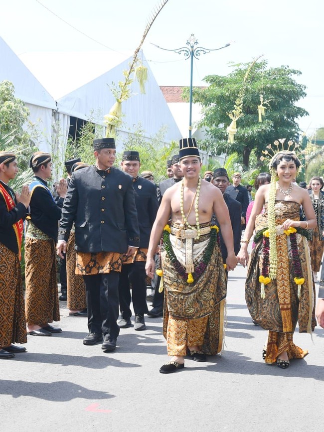 Kaesang menggunakan kain batik yang dililitkan seperti sarung. Kain batik motif blumbungan tersebut diikat dengan ikat pinggang emas. Dia juga memakai kuluk mathak atau topi yang memanjang ke atas.Foto: Foto: Pradita Utama/detikcom