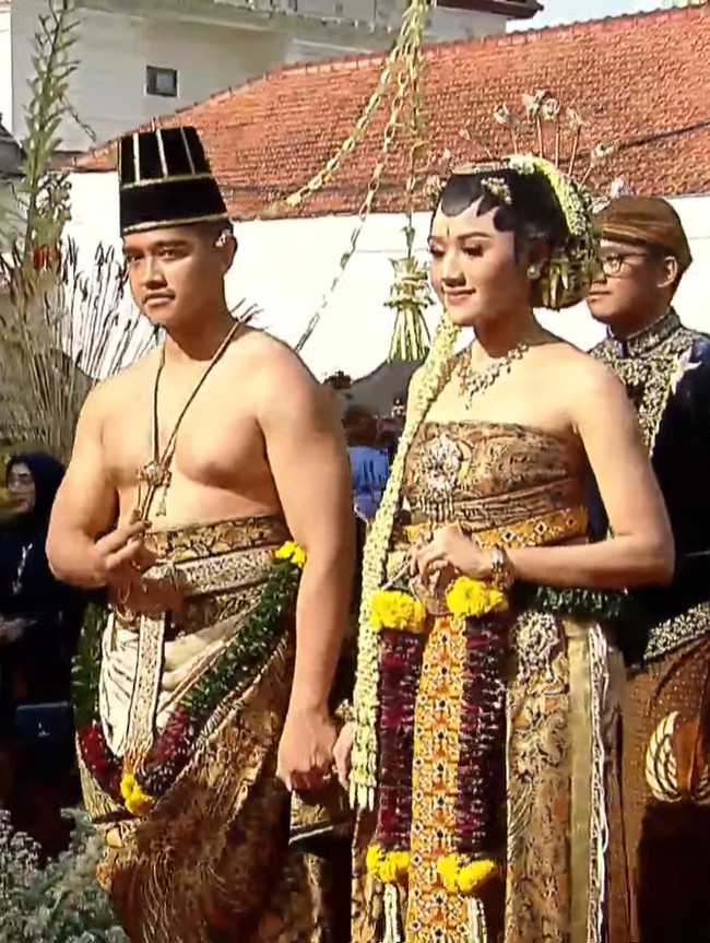Sementara Erina menggunakan kain panjang dililit di dada seperti kemben. Dodotan pengantin wanita pada busana Solo Basahan terdiri dari kain dodot hijau yang dipadu prada emas bermotif alas-alasan beserta motif blumbangan. Lalu ada stagen, udet cinde sebagai ikat pinggang, januran dan buntal udan emas.Foto: dok. Tangkapan layar YouTube Jokowi