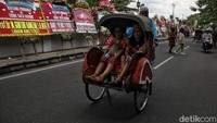 Warga dengan naik becak melintas di depan karangan bunga untuk Kaesang-Erina.