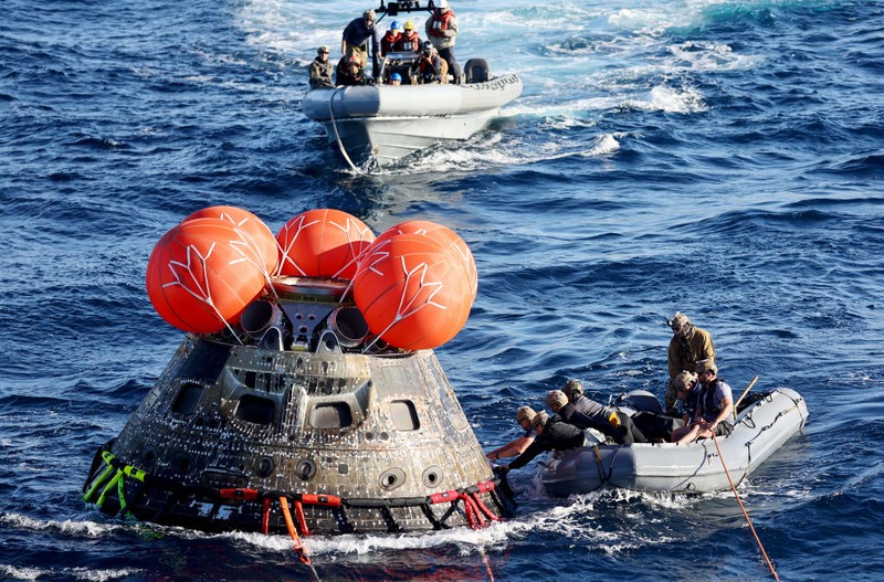 AT SEA, PACIFIC OCEAN - DECEMBER 11: U.S. Navy divers secure NASA's Orion Capsule during recovery operations after it splashed down following a successful uncrewed Artemis I moon mission on December 11, 2022 seen from aboard the U.S.S. Portland in the Pacific Ocean off the coast of Baja California, Mexico. A 26-day mission took the Orion spacecraft to the moon and back which completed a historic test flight that coincided with the 50th anniversary of the landing of Apollo 17 on the moon, the last time that NASA astronauts walked there. (Pool photo by Mario Tama/Getty Images)