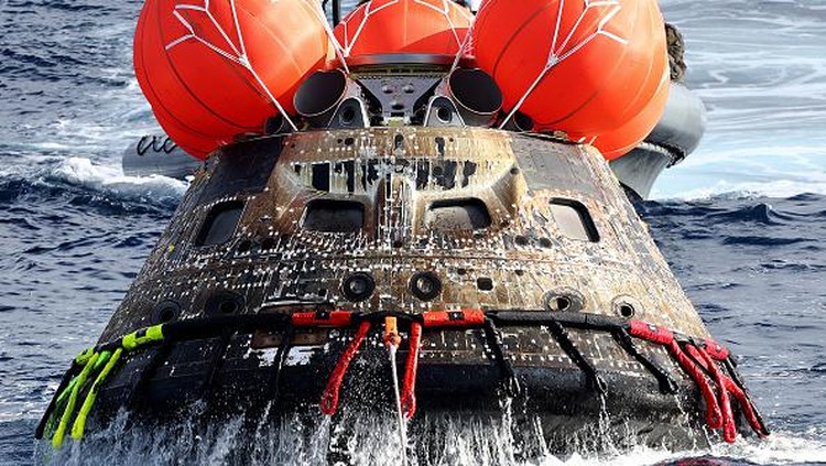 AT SEA, PACIFIC OCEAN - DECEMBER 11: NASAs Orion Capsule descends toward splash down after a successful uncrewed Artemis I Moon Mission on December 11, 2022 seen from aboard the U.S.S. Portland in the Pacific Ocean off the coast of Baja California, Mexico. A 26-day mission took the Orion spacecraft to the moon and back which completed a historic test flight that coincided with the 50th anniversary of the landing of Apollo 17 on the moon, the last time that NASA astronauts walked there. (Pool photo by Mario Tama/Getty Images)