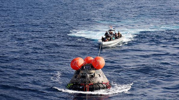 25 Hari Keliling Bulan, Kapsul Orion NASA Kembali ke Bumi AT SEA, PACIFIC OCEAN - DECEMBER 11: NASAs Orion Capsule descends toward splash down after a successful uncrewed Artemis I Moon Mission on December 11, 2022 seen from aboard the U.S.S. Portland in the Pacific Ocean off the coast of Baja California, Mexico. A 26-day mission took the Orion spacecraft to the moon and back which completed a historic test flight that coincided with the 50th anniversary of the landing of Apollo 17 on the moon, the last time that NASA astronauts walked there. (Pool photo by Mario Tama/Getty Images)